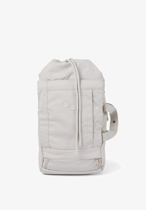Beiger Rucksack mit Kordelzug, Vorderfächern, zwei runden Knöpfen, seitlichem Griff und Reißverschlussfach am Boden.
