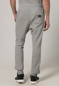 Grå mjukisbyxor med avslappnad passform, elastisk midja, sidofickor och en enda bakficka med en liten logotag.