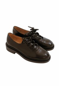 Scarpe di pelle nere con finitura lucida, con punte tonde e suola piatta. Presentano lacci decorativi e un design strutturato.