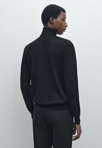 Schwarzer Rollkragensweater mit langen Ärmeln, aus weichem Material gefertigt. Figurbetonte Silhouette, gerippte Bündchen und Saum, minimalistisches Design.