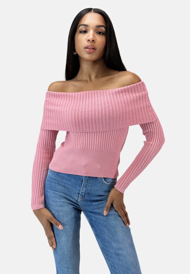 Rosa gerippter, schulterfreier Pullover mit langen Ärmeln, der ein geschichtetes Design und eine glatte Textur aufweist, kombiniert mit blauen Denim-Jeans.