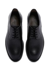 Zwarte leren schoenen met perforaties, platte veters en een ronde neus. Glad textuur met een subtiele glans en een contrasterende zool.