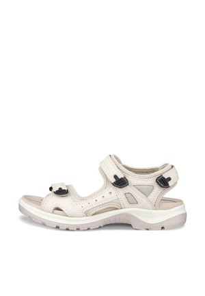 Sandale beige à bout ouvert avec brides noires réglables, semelle rembourrée et panneaux en mesh respirant, conçue pour le confort et le soutien en extérieur.