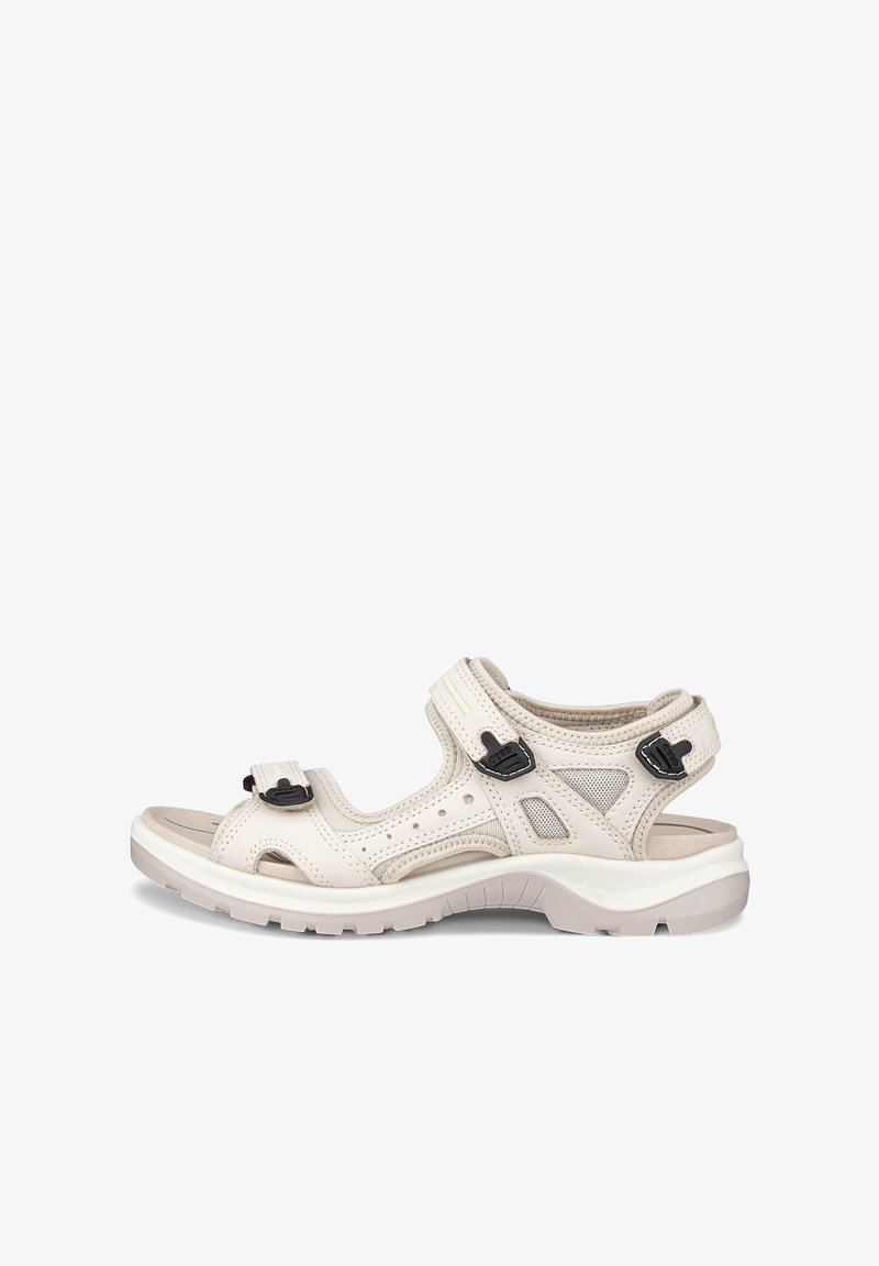 Sandale beige à bout ouvert avec brides noires réglables, semelle rembourrée et panneaux en mesh respirant, conçue pour le confort et le soutien en extérieur.