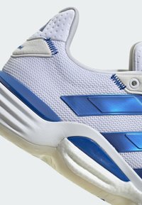 Biała sportowa sneaker z teksturowaną siateczką na górze i niebieskimi syntetycznymi akcentami. Posiada amortyzowaną podeszwę i wzmocniony obcas dla lepszego wsparcia.