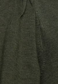 Pull en mailles vert olive avec un tissu texturé, un col rond et des coutures discrètes le long des épaules et des côtés.