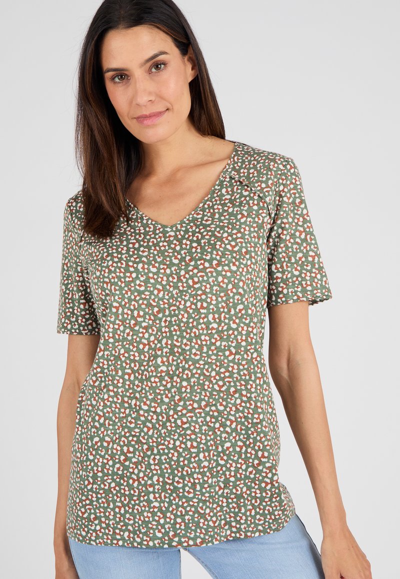 Camisa de manga corta y escote en V de tela verde con un patrón variado de manchas blancas y naranjas. Corte sencillo y relajado con una textura suave.