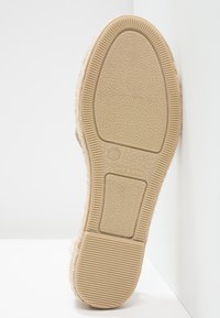 Sola della scarpa di un beige chiaro con gomma testurizzata per grip. Presenta un logo in rilievo e un'area del tacco liscia e arrotondata. Prodotto in Spagna.