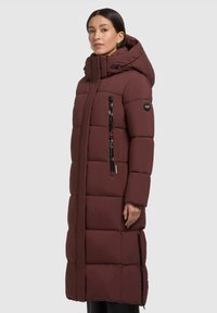 Langer burgunderfarbener Puffer-Mantel mit Kapuze, ausgestattet mit einem zipbaren Vorderreißverschluss, zwei seitlichen Taschen und gestepptem Muster zur Isolierung.
