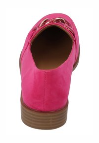 Zapato de ante rosa tipo slip-on con punta redondeada, que presenta detalles de hardware metálico y una suela marrón texturizada. No tiene marcas de marca visibles.