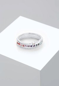 Bague en argent avec anneau torsadé et pierres précieuses multicolores disposées en dégradé autour du dessus, présentée sur un socle blanc.