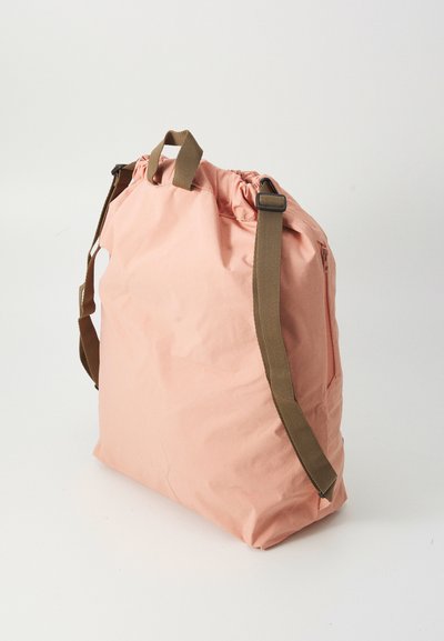 Rosa Stofftasche mit weicher Textur, verstellbaren braunen Trägern, Kordelzugverschluss oben und rechteckiger Form.