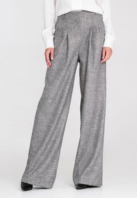 Szare szerokie spodnie z fakturowanej tkaniny, z przodu z zakładkami, w wysokim pasie i gładkim wykończeniu, zestawione z białą bluzką.