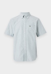 Short-sleeve button-up shirt in light blue fabric, featuring a pointed collar, a front pocket, and a small iconic logo on the chest.