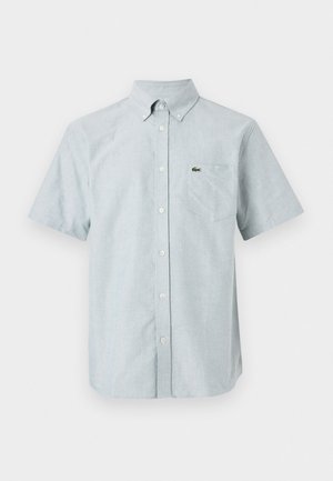 Kurzärmliges Button-Up-Hemd aus hellblauem Stoff, mit einem spitzen Kragen, einer Brusttasche und einem kleinen ikonischen Logo auf der Brust.