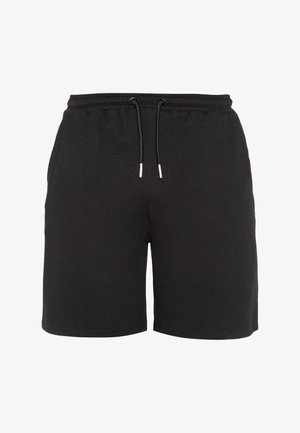 Schwarze strukturierte Shorts mit einem elastischen Bund und schwarzen Kordeln mit silbernen Enden, gezeigt vor weißem Hintergrund.