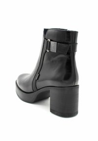 Stivale nero in pelle sopra la caviglia con tacco curvo, zip laterale e una fascia decorativa con accentuazione metallica. Texture liscia e design robusto.