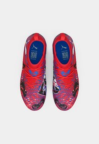 Baskets de sport rouges avec tige en maille, design texturé, accents bleus et motifs noirs contrastants. Présente un bout arrondi et un système de laçage.