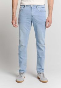 Lichtblauwe denim jeans met een slim fit, vijf-pocketontwerp, subtiele stikselaccenten en een rechte pijp, gecombineerd met grijze sneakers.