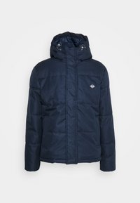 Mörkblå vadderad jacka med huva, försedd med dragkedja och knäppning med tryckknappar, slät yta och en liten logga på övre vänstra sidan.