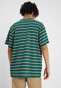 Grønstribet kortærmet t-shirt med pink og hvide vandrette linjer. Løs pasform og rund halsudskæring. Materiale i bomuldsblanding.