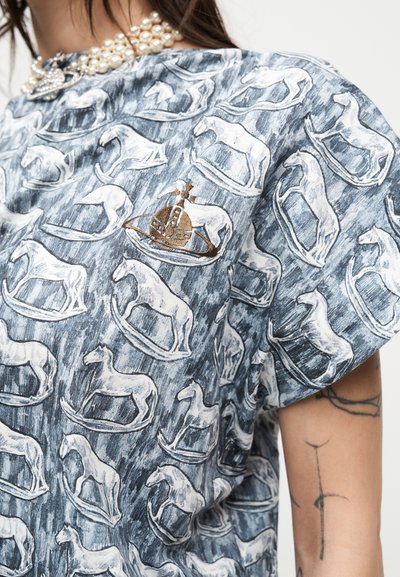 Πουκάμισο με επαναλαμβανόμενο μοτίβο λευκού αιωρούμενου αλόγου σε γκρι φόντο, με καφέ κεντημένο έμβλημα κορώνας κοντά στον ώμο.