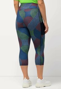 Multikleurige legging met een geometrisch patroon, met blauwe, groene en rode cirkelvormige ontwerpen, gemaakt van rekbare stof, met een cropped lengte.