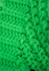 Bright green knit fabric with a textured pattern, featuring thick strands and a soft, fluffy appearance.