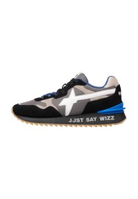 Sneaker nera, beige e grigia con logo a stella bianca, dettaglio del tallone blu e testo "JUST SAY WIZZ" sulla suola nera.