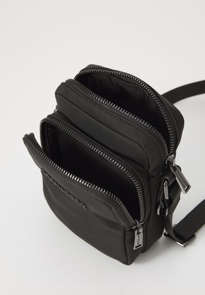 Czarna nylonowa torba na ramię z wieloma zapinanymi na zamek przegrodami. Posiada wytrzymałe zamki błyskawiczne i gładką teksturę. Kompaktowy i funkcjonalny design.