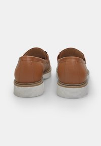 Kontrasterende lædersko i tan med struktureret overflade, rund hæl og en hvid, rillede sål. Designet til komfort med slip-on stil.