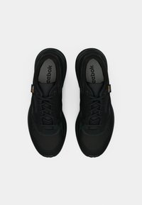 Um par de sapatilhas Reebok pretas com atacadores, tecido em malha e cordura, exibidas de cima sobre um fundo branco simples.