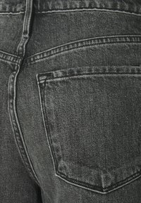 Svarta jeans i denim med en texturerad tyg, som har en bakficka och kontrastsöm längs sömmarna. Klassisk design med fem fickor.