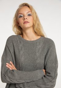 Grauer Strickpullover mit weitem Ausschnitt und gerippten Mustern. Lockere Passform und weiche Textur, mit verlängerten Ärmeln und entspanntem Design.