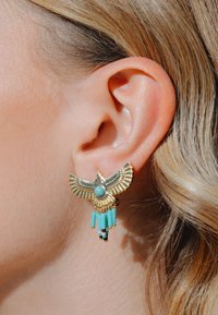 Boucle d'oreille en or en forme d'oiseau avec des accents en turquoise et des perles suspendues. Présente des détails complexes et des textures variées. Convient pour les oreilles percées.