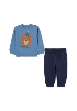 Sudadera azul de manga larga con un gráfico de un oso y texto, combinada con pantalones de forro polar azul marino con cintura elástica.