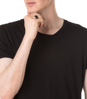 Black short-sleeve t-shirt worn by a person, holding their chin. A black ring is on the left hand. The background is plain white.