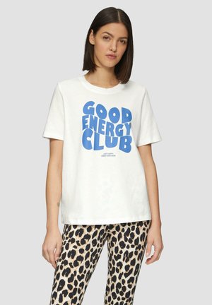 T-shirt en coton blanc à manches courtes arborant le texte bleu audacieux "GOOD ENERGY CLUB". Associé à des leggings à imprimé léopard pour un contraste.