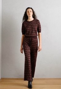 Burgunderfarbenes, gemustertes Zweiteiler-Outfit bestehend aus einem kurzärmeligen Oberteil und einer weiten Hose. Geschmeidiger Stoff mit einem Kordelzugbund und dezenten Akzenten.