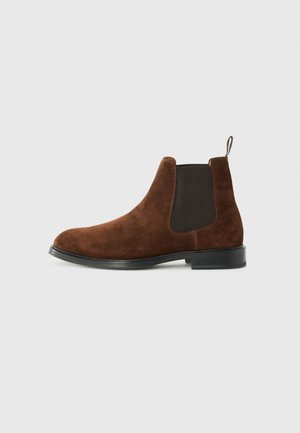 Brown suede Chelsea boots with black elastic side panels, a rounded toe, pull tab at the heel, and a low black heel.