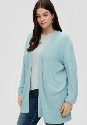 Cardigan texturé bleu clair avec un col en V et des manches longues, superposé à un haut gris, associé à un jean foncé.