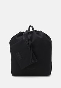 Sac à dos en tissu noir avec un haut resserré, des accents en cuir et une pochette zippée détachable. Présente un design minimaliste et une texture lisse.