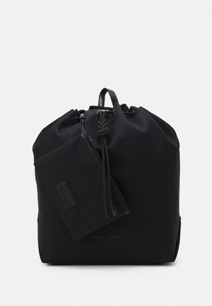 Sac à dos en tissu noir avec un haut resserré, des accents en cuir et une pochette zippée détachable. Présente un design minimaliste et une texture lisse.