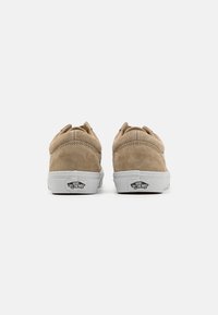 Smeđe suede tenisice s bijelim gumiranim potplatima. Značajke uključuju zaobljeni vrh, podstavljeni ovratnik i šivane detalje. Logo se nalazi na peti.