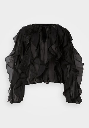 Zwarte doorschijnende blouse met ruches, lange mouwen en een keyhole-halslijn. De stof is lichtgewicht en vloeiend, wat volume creëert.