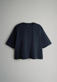 Granatowa koszulka z krótkim rękawem, wykonana z gładkiego materiału, posiadająca okrągły dekolt i luźny, pudełkowy krój. Bez widocznych wzorów czy akcentów.