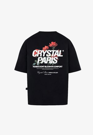 Czarna, oversize koszulka z czerwoną grafiką róży i białym napisem: "CRYSTAL PARIS" oraz "ROSES DONT BLOOM IN COMFORT" na plecach.