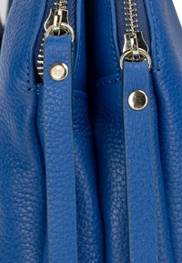 Borsa a mano blu in pelle con due zip dorate, caratterizzata da una finitura testurizzata e un design strutturato. Accenti in metallo dorato sono visibili.