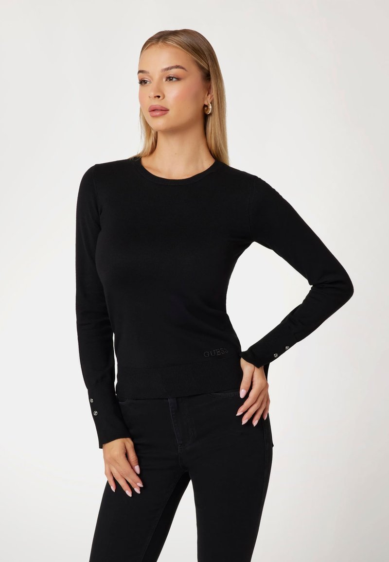 Pull noir ajusté en maillot lisse. Doté de manches longues avec des accents de boutons aux poignets et d'un ourlet côtelé, affichant le logo de la marque.