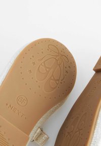 Helle Ballettschuhsohle mit einem geprägten Ballettschuhdesign, das eine glatte Textur, eine abgerundete Form und ein flexibles Gummimaterial aufweist.
